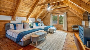 A wooden cabin bedroom with a large bed, two bedside tables, a desk, and a window. - Grand Mountain Lodge, Pickleball, Barrel Sauna, Hot Tub, Game Room, Arcade (Luray)