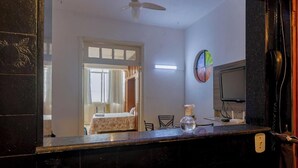 A room with a bed, a desk, a chair, a television, and a mirror. - Apto no Rio a 200m da Praia de Copacabana (Rio de Janeiro)
