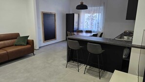 Une cuisine moderne dotée d’un îlot central, de tabourets de bar et d’un coin repas avec un canapé en cuir marron.