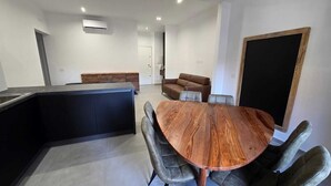 Une cuisine moderne avec un plan de travail foncé, une table à manger en bois avec des chaises et un banc intégré.