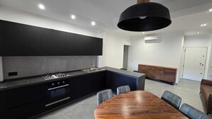 Une cuisine moderne dotée d’un îlot central, d’un four encastré et d’un coin repas avec une table et des chaises en bois.