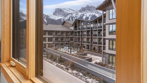 A modern building with multiple balconies and a view of snow-capped mountains. - Luxury Modern Mountain Lodge in Spring Creek, Canmore (Canmore)