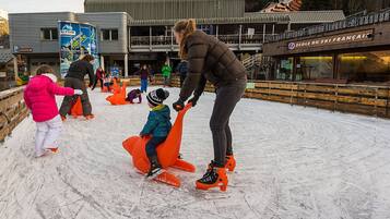 Ein verschneiter Außenbereich mit Menschen, die winterliche Aktivitäten ausüben.