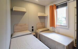 A small, compact room with two single beds, a window with orange curtains, and a wall-mounted shelf. - 2 bedroom stunning home in Tarquinia (Tarquinia)