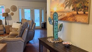 Ein Wohnzimmer mit einem Ledersofa, einem Holztisch und einem Bild einer Strandansicht.