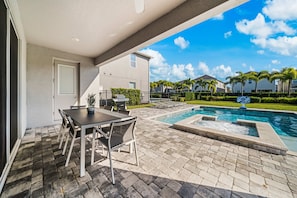 A patio with a pool, outdoor furniture, and a view of a residential area.