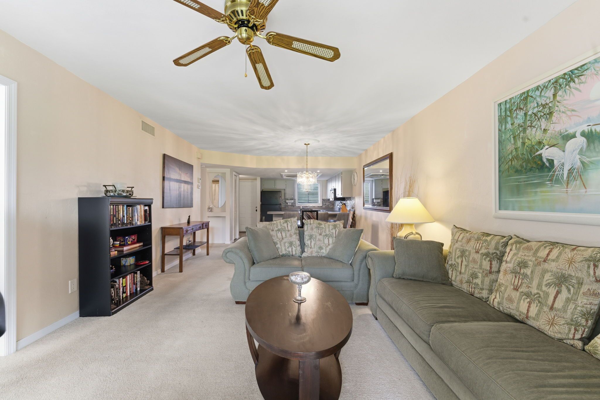 A living room with a ceiling fan, a sofa, a coffee table, and a bookshelf.