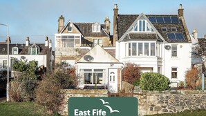 En traditionel feriebolig fra East Fife med en stenfassade, flere vinduer og en lille veranda.