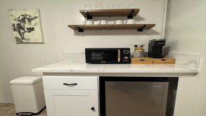 Eine kleine Küche mit Mikrowelle, Kaffeemaschine und einem Hängeschrank.