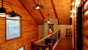 A wooden interior with a wooden staircase, a ceiling fan, and a window with a view of trees. - Secluded Mountain Cabin near Scenic Lakes & Trails (Hot Springs)