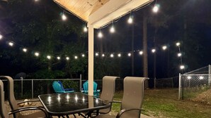 An outdoor patio with a table and chairs, string lights, and a view of the surrounding area. - Secluded Mountain Cabin near Scenic Lakes & Trails (Hot Springs)