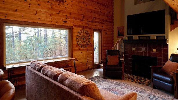A cozy cabin interior with a large window, a fireplace, and a comfortable seating area. - Secluded Mountain Cabin near Scenic Lakes & Trails (Hot Springs)