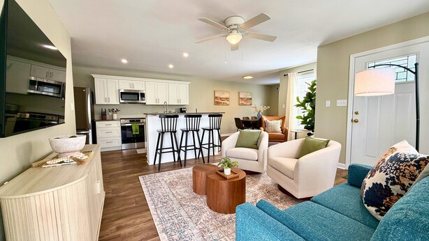 A modern living room with a blue sofa, a coffee table, and a dining area with a kitchen in the background.