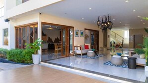Een ruime lobby met een modern design, met een zithoek met een bank en stoelen, een trap en een kroonluchter.