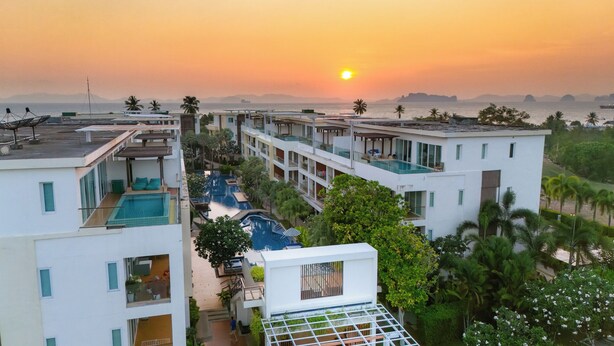 Een resort met meerdere zwembaden, een rooftop bar en uitzicht op de ondergaande zon boven de oceaan.