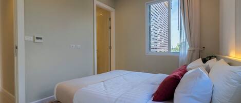 Een slaapkamer met een bed, een raam met zonwering, een deur en een thermostaat aan de muur.