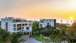 Een meerhoog hotel met balkons, schotels en een aangelegde tuin.