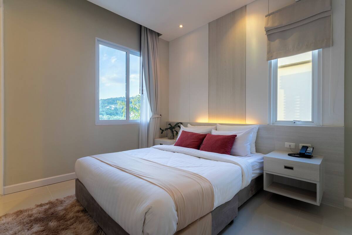 Une chambre moderne avec un grand lit, des tables de chevet et une vue sur l’extérieur.