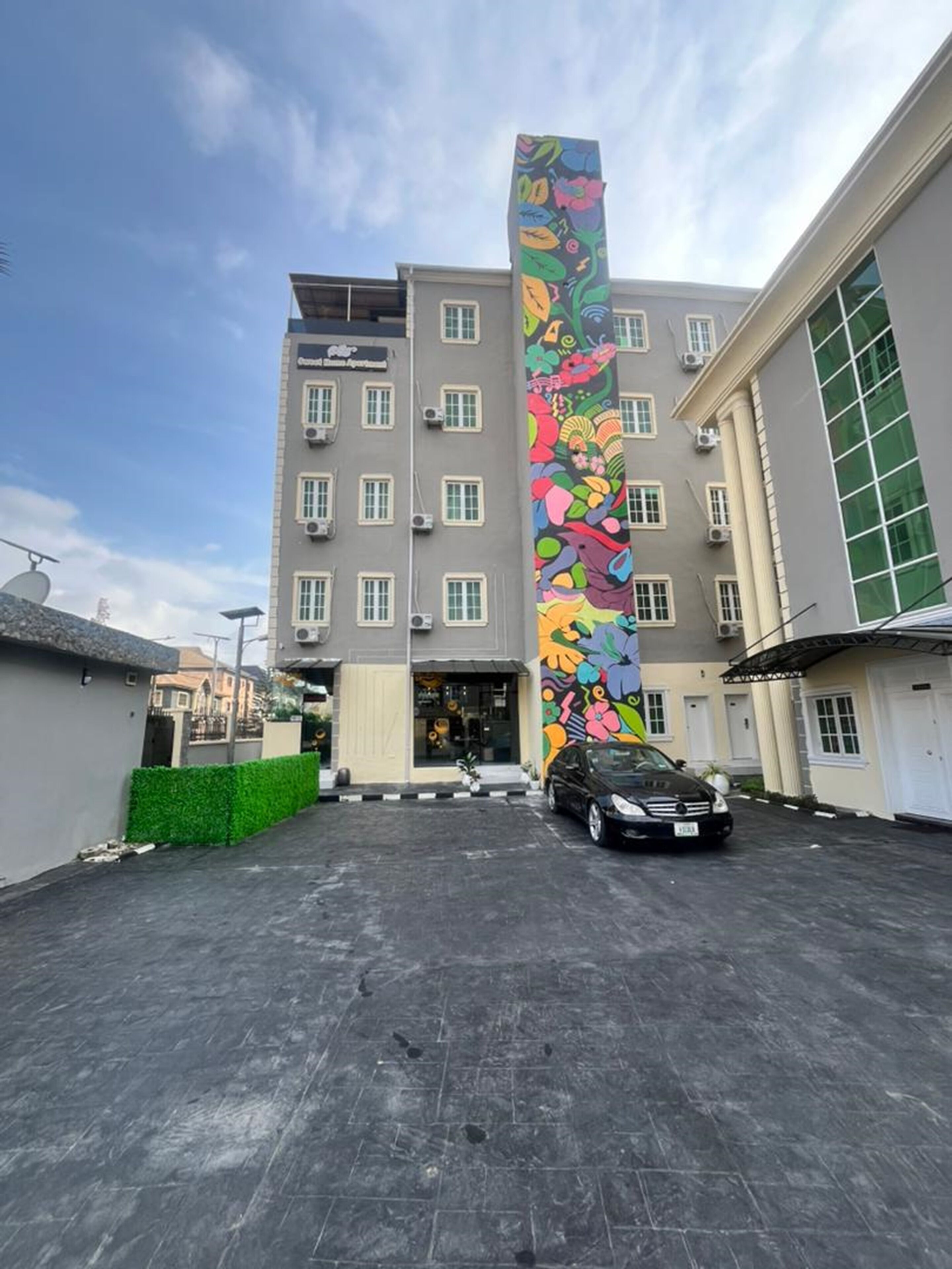 Un immeuble à plusieurs étages dont la façade est ornée d’une fresque verticale aux couleurs vives.