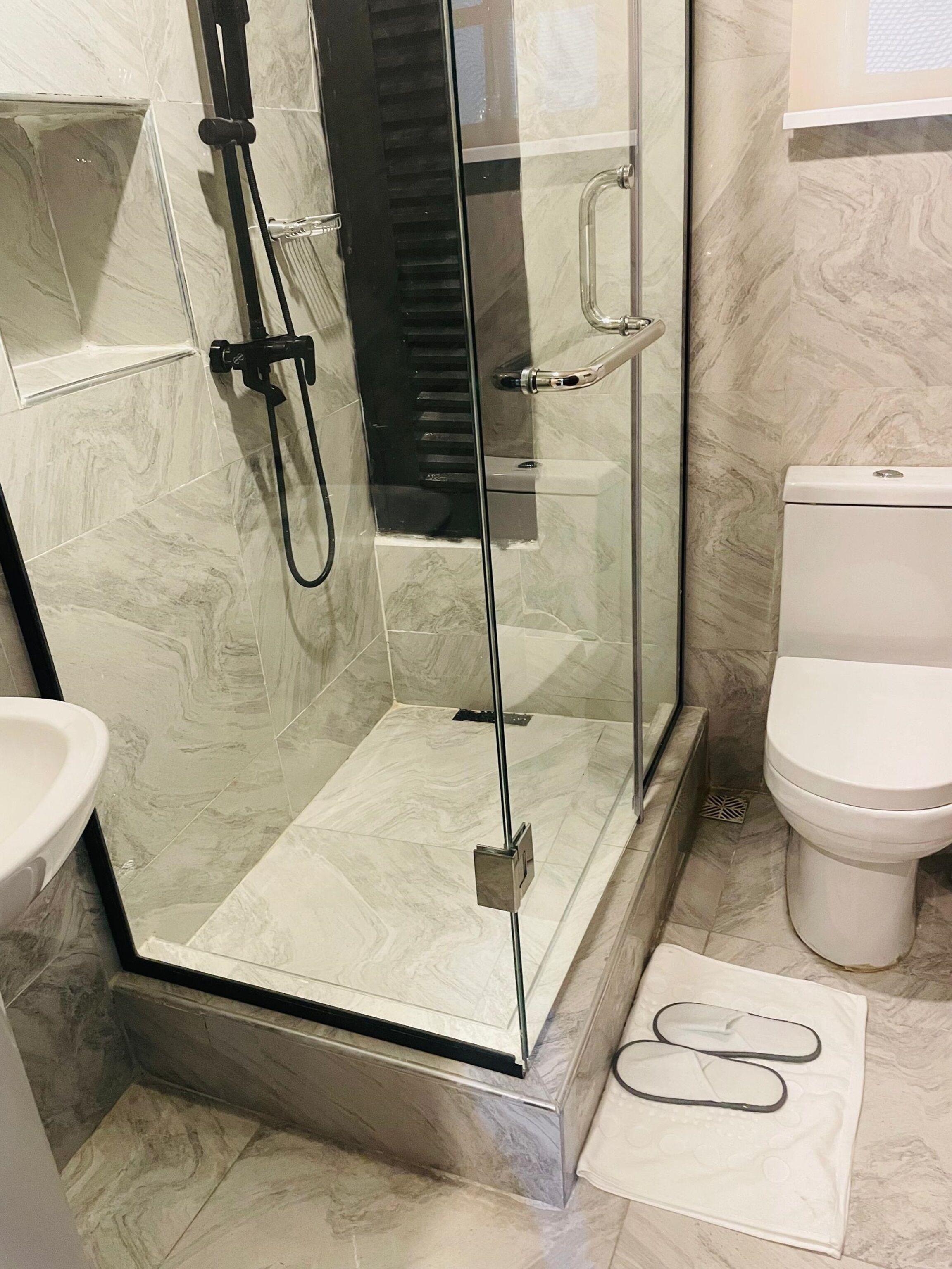 Une salle de bain avec une douche à parois de verre, des toilettes et un lavabo.
