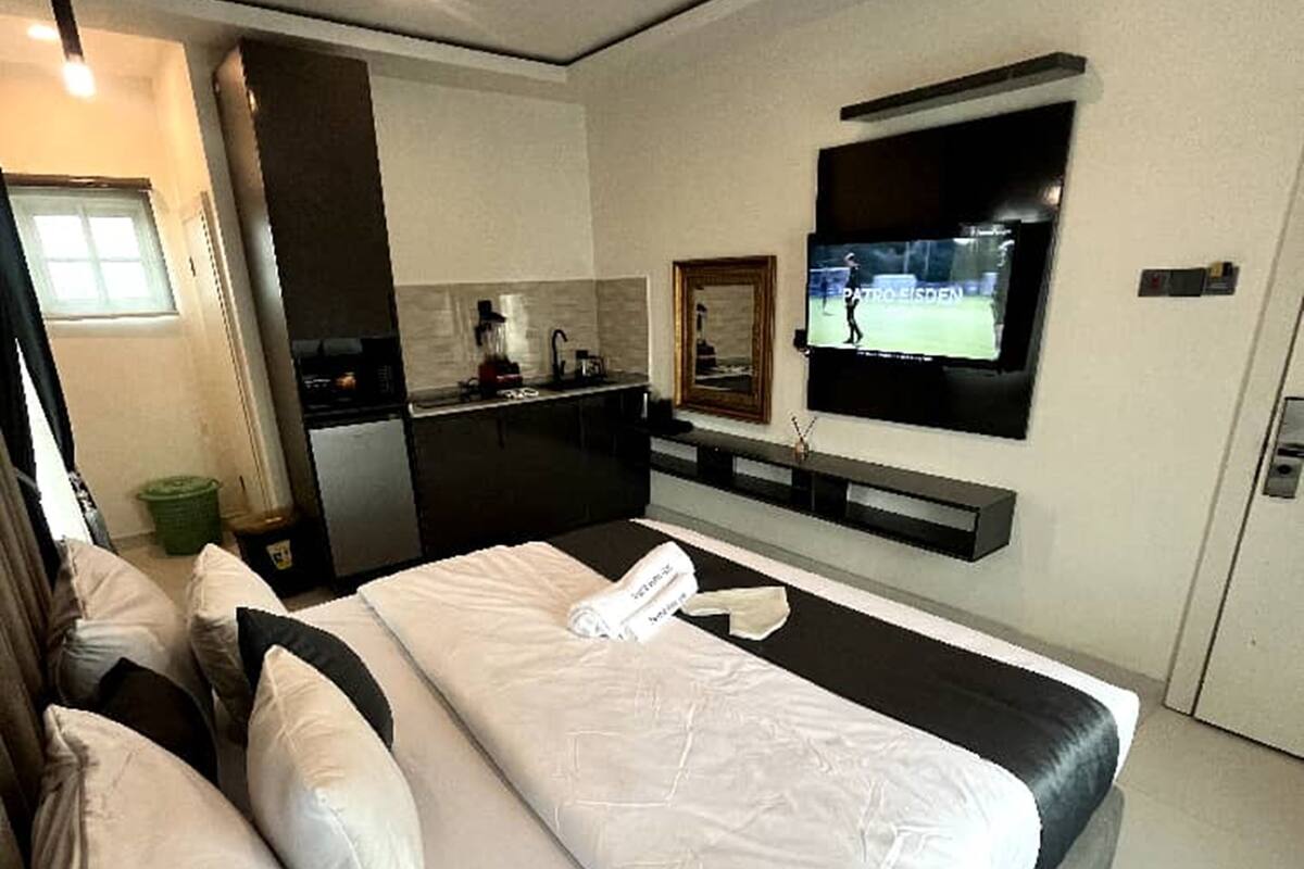 Een moderne hotelkamer met een groot bed, een flatscreen televisie aan de muur en een kitchenette.