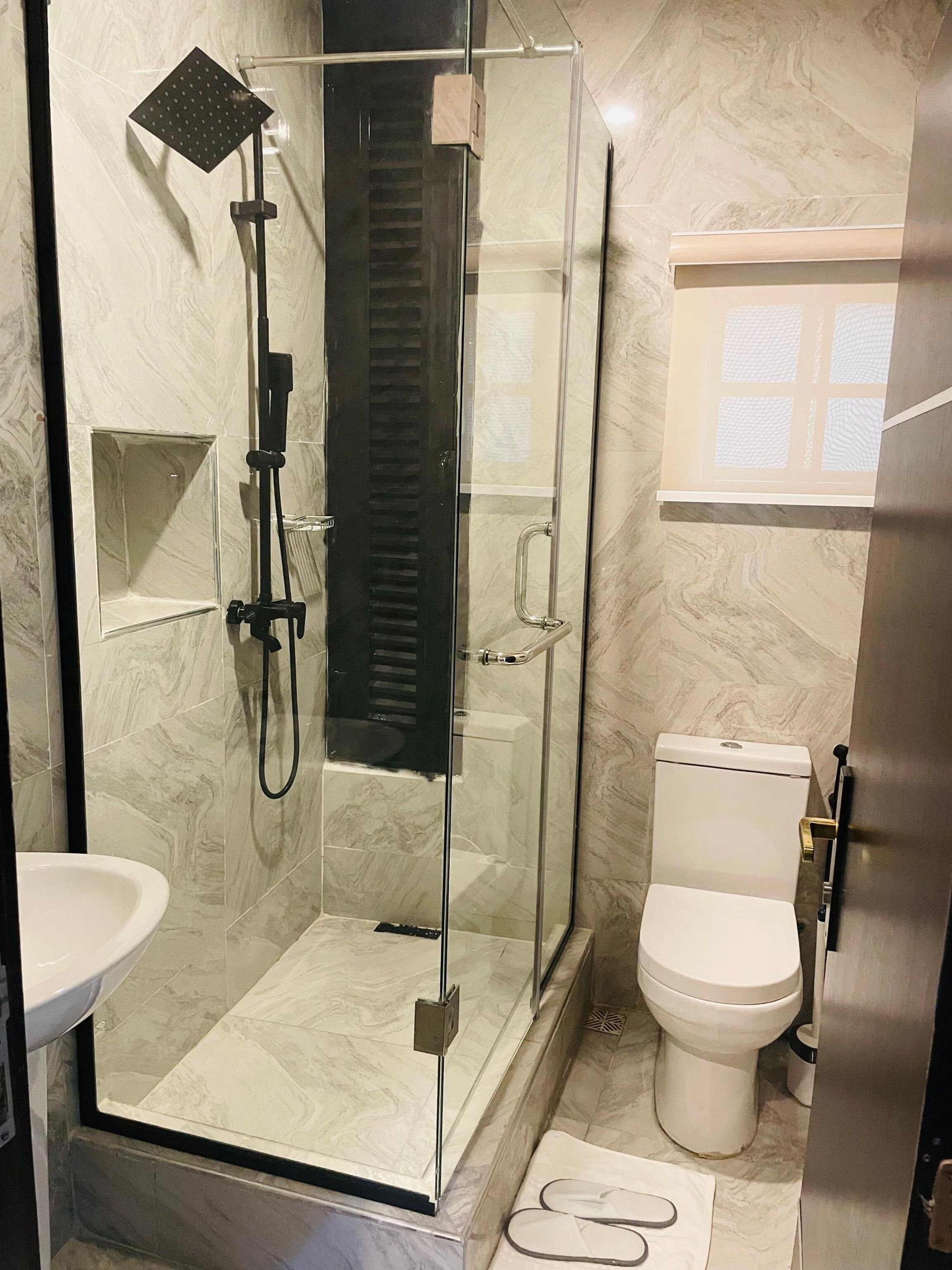 Ein modernes Badezimmer mit einer Duschkabine aus Glas, einer weißen Toilette und einem Waschbecken.