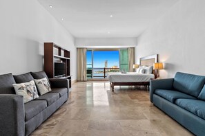 A spacious hotel room with a large bed, a sofa, a TV, and a balcony with a view of the city. - Penthouse Oceanview, Free Shuttle at Deck12 (Puerto Vallarta)