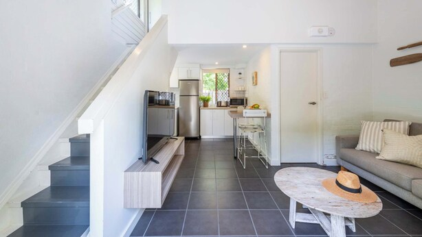 Une cuisine moderne équipée d’un réfrigérateur, d’un four à micro-ondes et d’une cuisinière, qui donne sur un coin repas avec une table et des chaises.