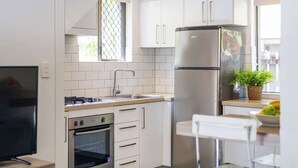A modern kitchen with white cabinets, stainless steel appliances, a built-in oven, and a sink. - Bayshore Bungalow 4 - Oceanstays (Byron Bay)