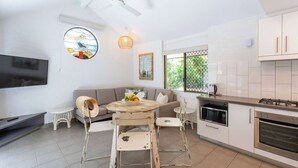 A modern kitchen with white cabinets, a built-in oven, and a dining area with a round table and chairs.
