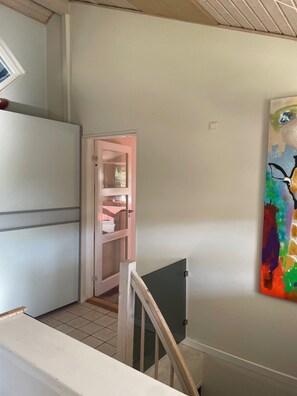 A staircase with a handrail, a door leading to a room with a window, and a colorful abstract painting on the wall. - Holiday oasis with terrace and sloping garden (Tikøb)