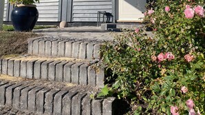 A house with a covered porch, a large potted plant, and a rose bush. - Holiday oasis with terrace and sloping garden (Tikøb)