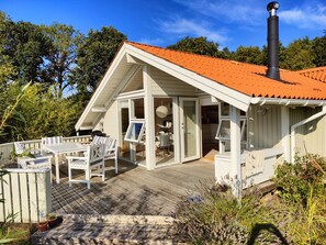 A house with a sloped roof, a deck with outdoor furniture, and a chimney. - Quiet cottage near nature water and views (Rude)