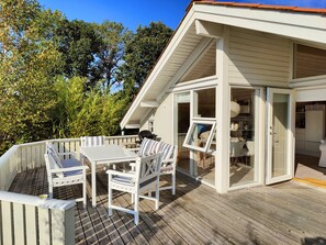 A deck with outdoor furniture, a grill, and a glass door leading to a kitchen. - Quiet cottage near nature water and views (Rude)