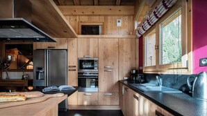 A modern kitchen with wooden cabinets, stainless steel appliances, and a large window providing natural light.