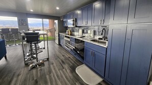A modern kitchen with dark blue cabinets, stainless steel appliances, and a bar area with stools. - 1 Bedroom Luxurious Loft perfect for Entertaining! (Colorado Springs)