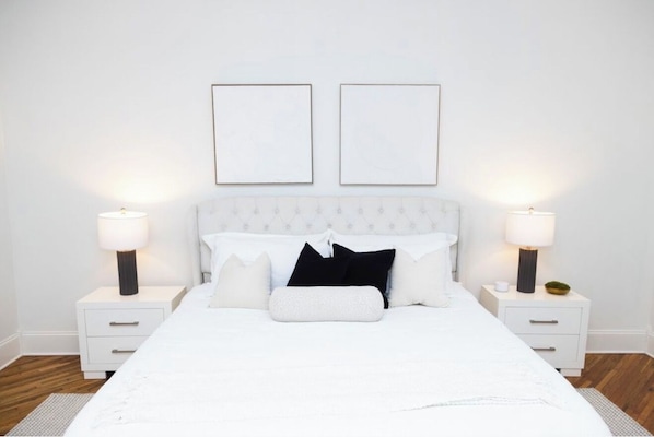 A neatly arranged bedroom with a bed, two bedside tables, and two wall-mounted picture frames.