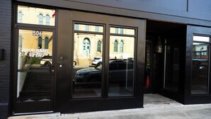 A building with a black facade, a numbered door (506), and large windows reflecting a street scene. - GOOD HABIT Spacious 4-bedroom loft apartment on the square in Springfield, TN (Springfield)