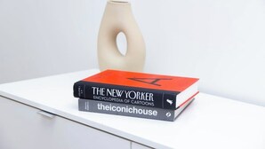 A white table with a vase and two books titled 'The New Yorker Encyclopedia of Cartoons' and 'The Iconic House.' - GOOD HABIT Spacious 4-bedroom loft apartment on the square in Springfield, TN (Springfield)