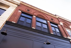 A building facade with a large garage door, a brick structure, and three windows with dark frames.
