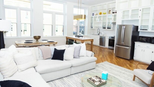 A modern kitchen with white cabinets, a stainless steel refrigerator, and a dining area with a white table and chairs. - GOOD HABIT Spacious 4-bedroom loft apartment on the square in Springfield, TN (Springfield)