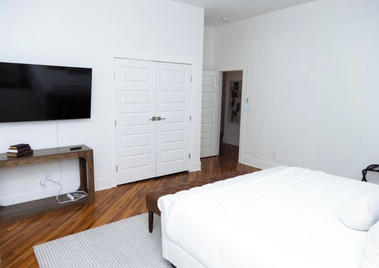 Ein Schlafzimmer mit Bett, Fernseher, Kleiderschrank und Schreibtisch.