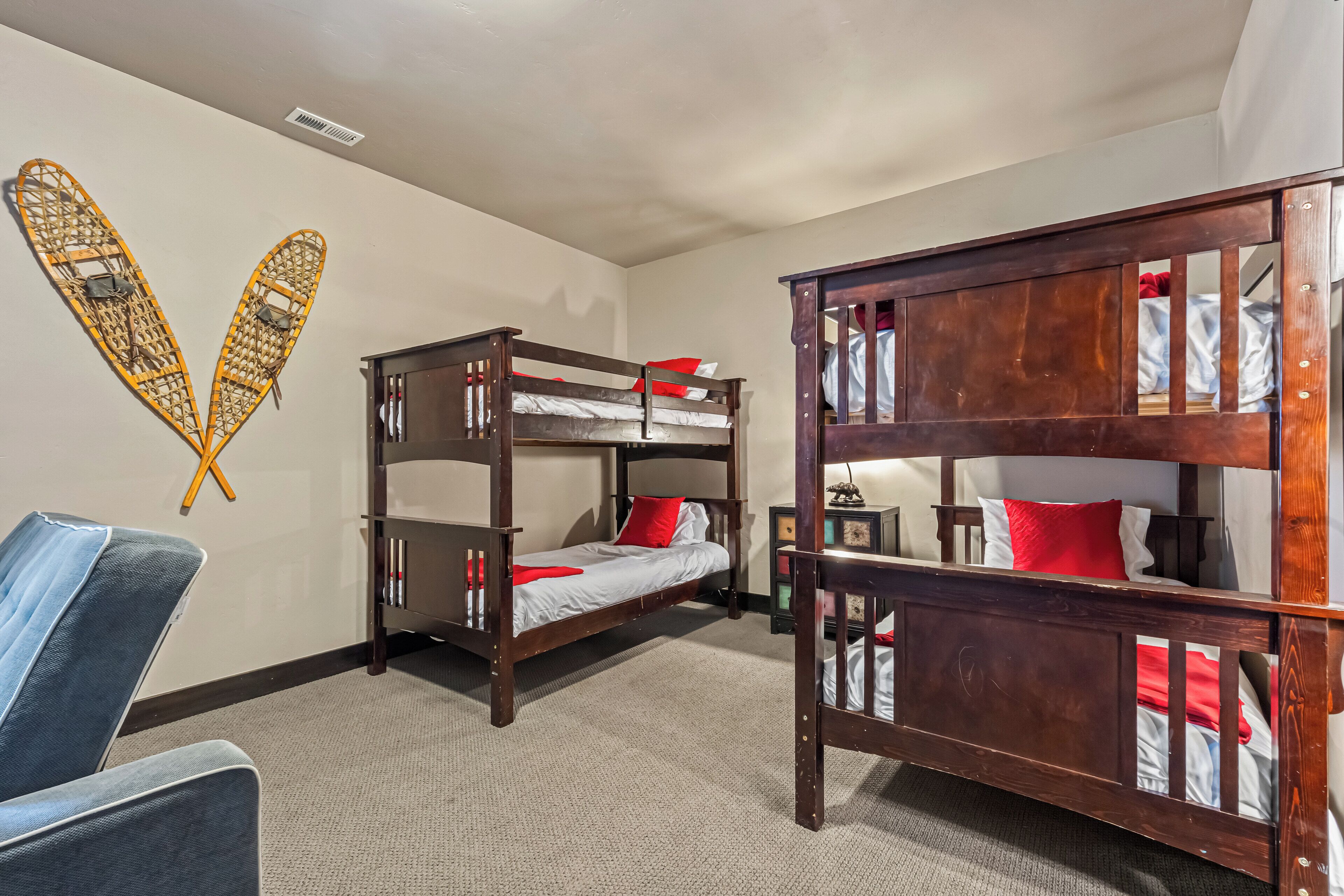 A room with bunk beds, a chair, and a wall decoration.