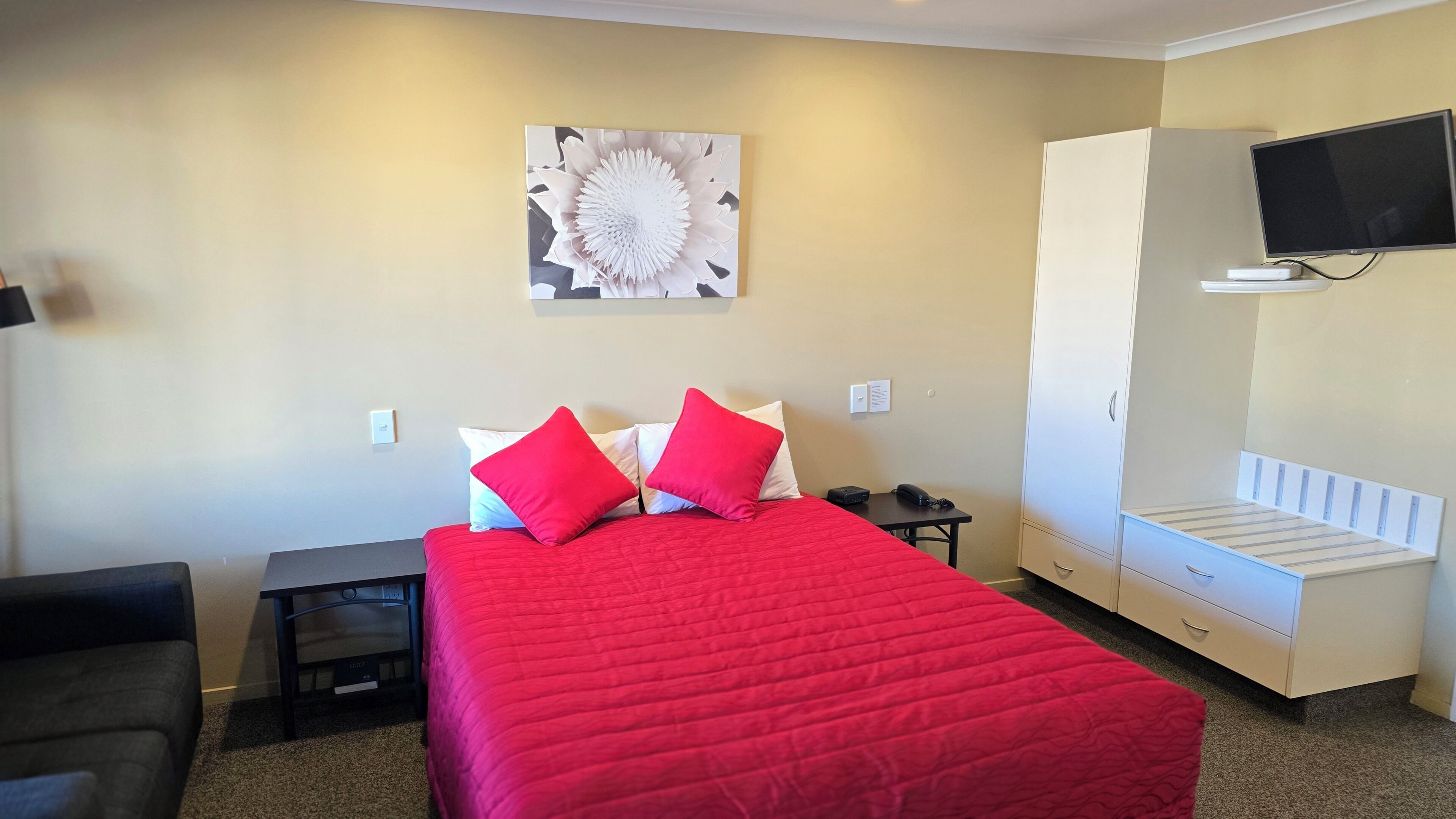 Una habitación de hotel con cama, escritorio, silla, televisor y armario.