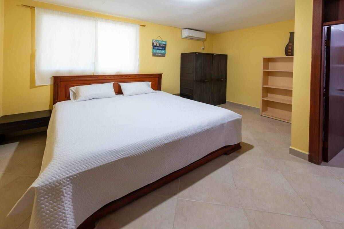 A bedroom with a large bed, a wardrobe, and a shelf unit.