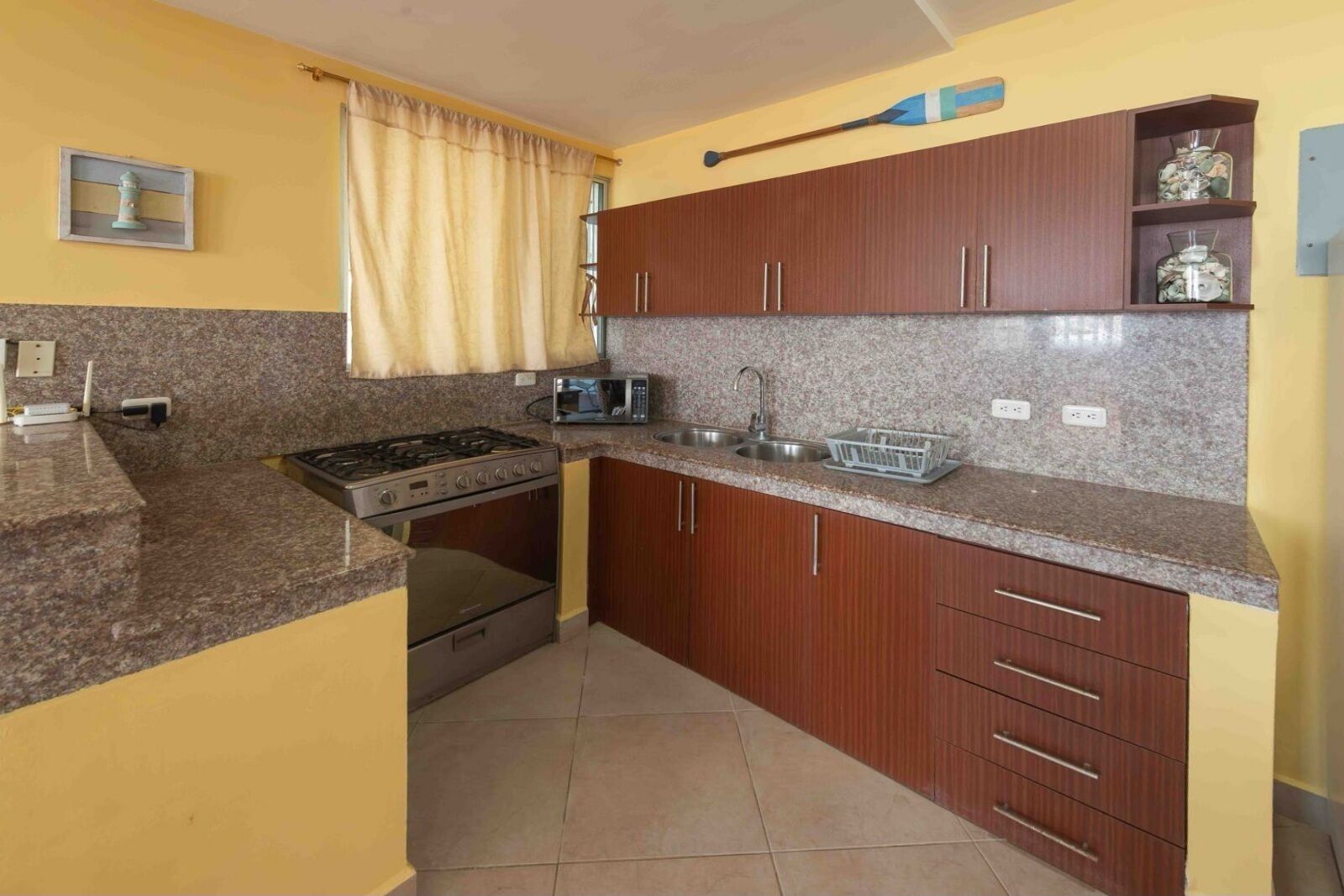 A compact kitchen with granite countertops, a gas stove, a microwave, and wooden cabinets.
