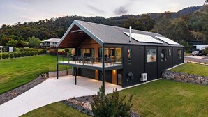 A modern house with a large balcony, solar panels, and a view of the surrounding hills. - Fiddle View | Alfresco Dining with Mountain Views (Tawonga South)