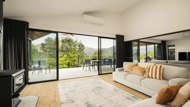 A modern living room with a large sliding glass door leading to an outdoor patio. - Fiddle View | Alfresco Dining with Mountain Views (Tawonga South)