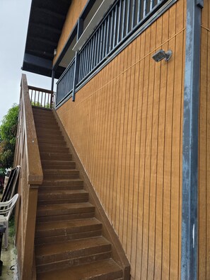 A wooden exterior with a metal railing and a staircase leading to a balcony. - Oceanview 2-bedroom apartment in Kealakekua Kona (Kealakekua)