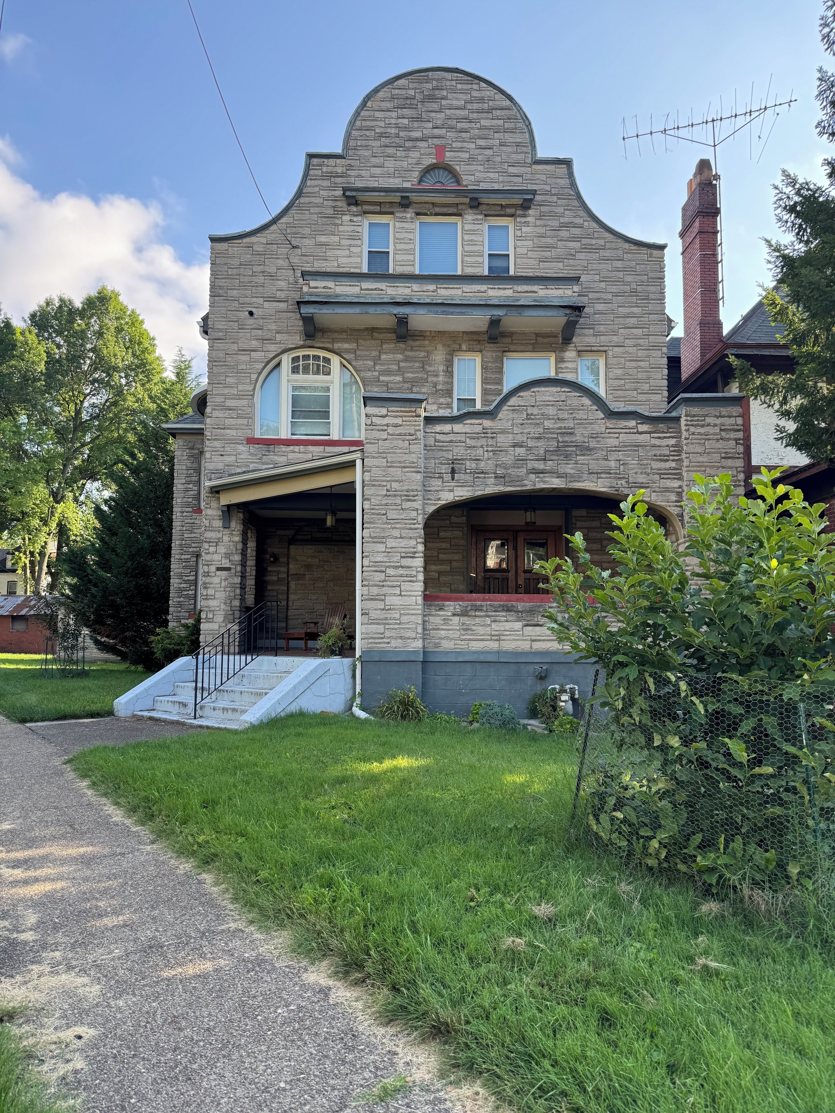 A two-story stone house with a garage, a front porch, and a chimney.